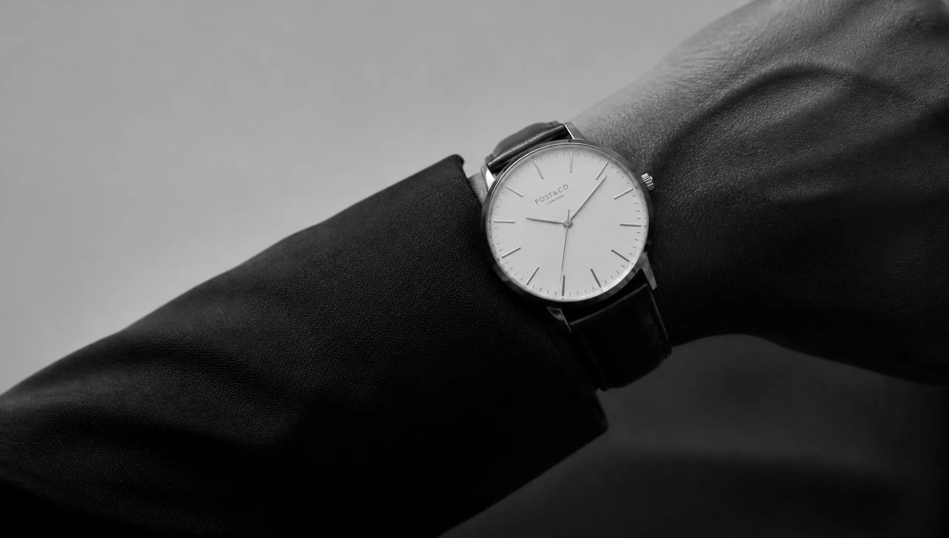 Black and white photograph of a minimalist watch on a wrist